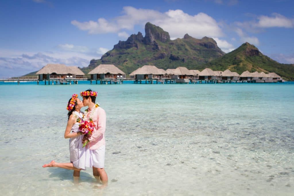 bride kissing in front of mount Otemanu in traditional pareo