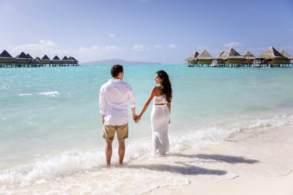 Livia & Marc holding hand with feet in the water