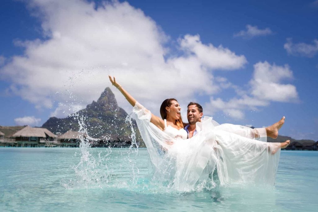 Couple splashing water and trashing the dress